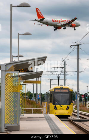 Stadt von Manchester Metrolink tram an der Shadowcross Station in der Nähe von Manchester Flughafen. Easyjet Flugzeug Landung geht über Kopf. Stockfoto