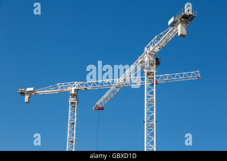 Zwei Turmdrehkrane arbeiten in London gegen blauen Himmel Stockfoto