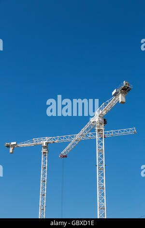 Zwei Turmdrehkrane arbeiten in London gegen blauen Himmel Stockfoto