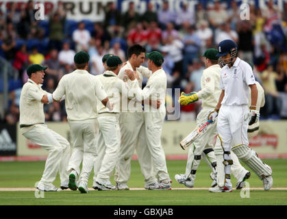 Der englische Alastair Cook geht niedergeschlagen los, nachdem er für 1 Uhr unterwegs war, als der australische Mitchell Johnson am vierten Tag des ersten npower-Test-Spiels in Sophia Gardens, Cardiff, feiert, das Wicket zu nehmen. Stockfoto