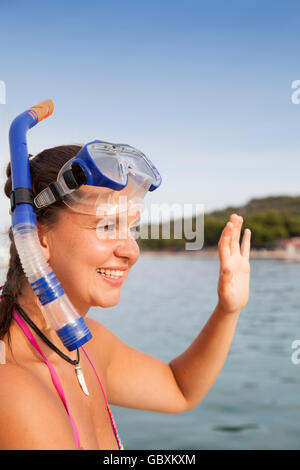 Schöne Mädchen am Meer trägt eine Taucherbrille und winken Hallo Stockfoto