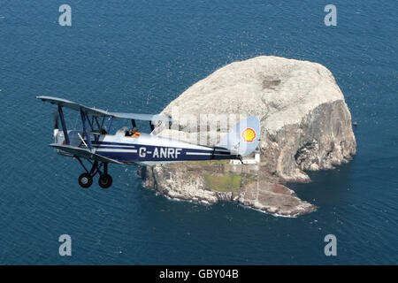 Ein Doppeldecker der Tiger Moth, der von David Cyster pilotiert wurde, manövriert über Bass Rock, East Lothian, vor der Airshow des National Museum of Flight in East Fortune. Stockfoto