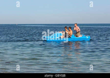 Drei junge Männer, die mit einem Drink auf Pedalo fahren Boot, Mittelmeer, Spanien Stockfoto