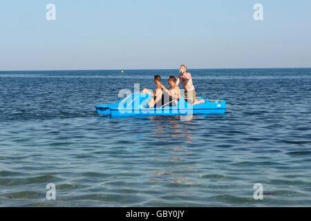 Drei junge Männer, die mit einem Drink auf Pedalo fahren Boot, Mittelmeer, Spanien Stockfoto