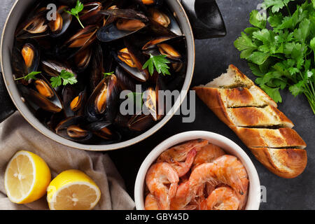 Muscheln und Garnelen mit selbstgebackenem Brot auf Holztisch. Ansicht von oben Stockfoto