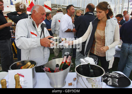 Am dritten Tag der Cowes Week, der weltbekannten Segelregatta, die jedes Jahr auf der Solent stattfindet, gießt ein Mann ein Glas Champagner in der Champagne Mumm Bar in Cowes Yacht Haven, aber anderswo gibt es keine Einnahmen. Die Organisatoren haben heute aufgehört, den Zuschauern wegen mangelnden Handels den Eintritt zu den Abendfesten zu berechnen. Stockfoto