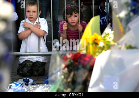 Jay Baton, 3, und Jessie Baton, 7, schauen auf Tribute neben einer Statue von Bobby Robson vor dem Fußballverein von Ipswich Town, in Erinnerung an den heute verstorbenen Fußballmanager Ipswich. Stockfoto