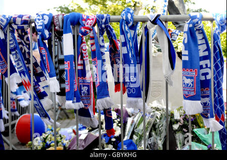 Blumenschmuck und Schals neben einer Statue von Bobby Robson vor der Portman Road, der Heimat des Fußballvereins Ipswich Town, in Erinnerung an den heute verstorbenen Fußballmanager Ipswich. Stockfoto