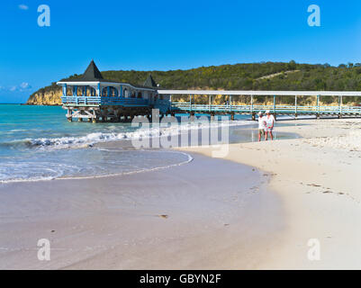 dh Dickenson Bay Beach ANTIGUA KARIBIK Touristenpaar zu Fuß Küste Warri Pier Restaurant West Indies Romantik Stockfoto