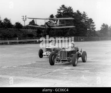 A de Havilland DH 82 Tiger Moth Flugzeug beobachtet Rennwagen, die für das 200 Meilen Rennen in Brooklands üben. Stockfoto