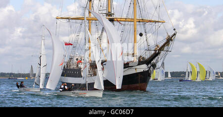 Die Laser SB3-Flotte geht vom dritten Start der Cowes Week auf der Isle of Wight aus dem Wind an dem Großschiff Pelican von London vorbei. Stockfoto