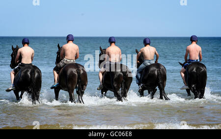 Truppen der Blues and Royals des Household Cavalry Mounted Regiment trainieren ihre Pferde im Meer, vor Holkham Beach, in Holkham, Norfolk während ihres dreiwöchigen Sommertrainingslagers und einer Pause von den zeremoniellen Pflichten. Stockfoto