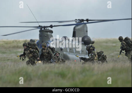 Soldaten des 1. Bataillons Royal Welsh ziehen mit einem Chinook-Hubschrauber im Hintergrund zu ihrem Ziel, der sie in die Trainingskampfzone in Brecon absetzte, während sie an einer Trainingsübung vor ihrer Mission in Afghanistan Anfang Oktober teilnehmen. Stockfoto
