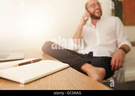 Tagebuch am Schreibtisch mit Mann sitzt im Hintergrund telefonieren mit Handy. Geschäftsmann, vom home-Office arbeiten.