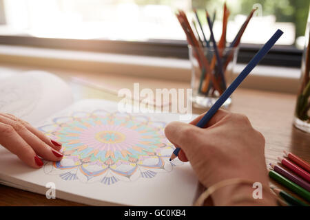 Nahaufnahme von Menschenhand zeichnen in Erwachsene Malbuch mit Buntstift zu Hause. Linderung von Stress mit Bleistift Färbung boo Stockfoto