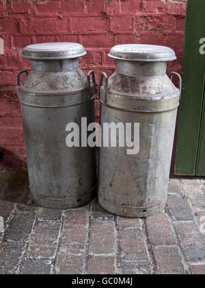 Paar Metall Milchkannen auf einem Ziegel-Fußboden. Stockfoto