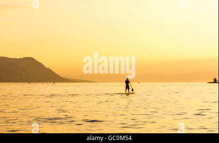 Eine einzelne Paddel-Boarder am Genfersee in der Schweiz bei Sonnenuntergang Stockfoto