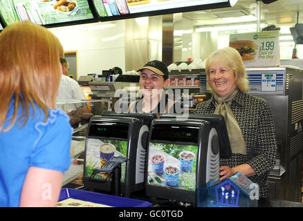 Kylie Blaney, 21 Jahre alt (Mitte) und ihre Großmutter Jean Bulmer (rechts), 62 Jahre alt, beide aus Haverfordwest in Wales, dienen hinter der Kasse im McDonald's Restaurant in der Oxford Street im Zentrum von London. Stockfoto