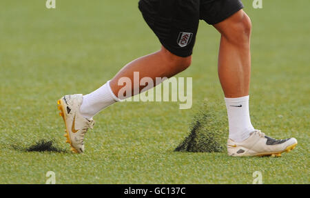 Material aus dem künstlichen Spielfeld wird als Fulham hochgeschmissen Die Spieler laufen Stockfoto