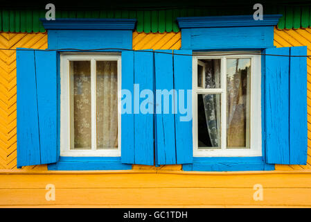 Zwei blaue Hand bemalte hölzerne Fensterrahmen auf eine gelbe Farbe bedeckt-Haus Stockfoto