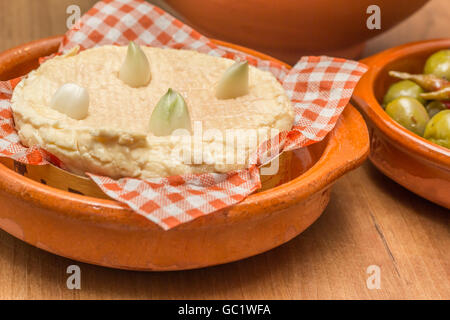 Französischer Camembert mit Knoblauchzehen auf einem Holztisch Stockfoto