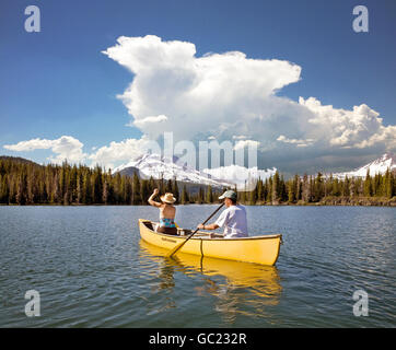 Ein verheiratetes Paar, Senioren, Kanu, camping auf Sparks Lake in Oregon Cascade Mountains entlang der Kaskade Seen-Autobahn. Schwestern Wildnis und South Schwestern Peak sind im Hintergrund. Stockfoto