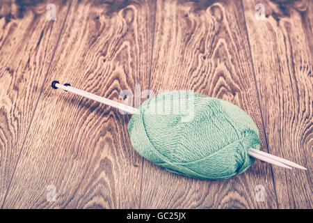 Retro stilisierte Garn mit Stricknadeln auf hölzernen Stock, Hobby oder Ruhestand Konzept. Stockfoto