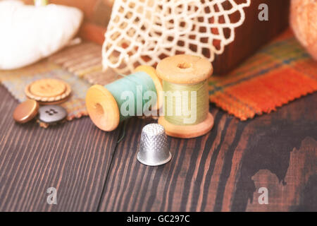 Spool-Thread, ein Fingerhut und eine Schachtel mit Handarbeiten auf einem Holztisch Nahaufnahme Stockfoto