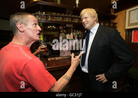 Wachsmodelle des Londoner Bürgermeisters Boris Johnson (der morgen auf BBC SOAP Eastenders zu Gast ist) und Barbara Windsor, als Charakter Peggy Mitchell, werden im Queen Victoria Pub in Southwark, London, mit dem lokalen Kunden Stephen Salmon aufgestellt. Stockfoto