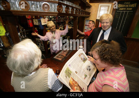 Wachsmodelle von Boris Johnson, dem Bürgermeister von London (der morgen auf BBC SOAP Eastenders zu Gast ist) und Barbara Windsor, als Figur Peggy Mitchell, werden im Queen Victoria Pub in Southwark, London, mit lokalen Kunden Theresa Salmon (links), Amanda Smith und Stephen Salmon (Hintergrund) platziert. Stockfoto