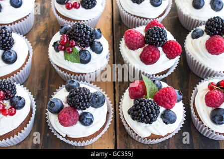 Cupcakes mit Früchten auf einem rustikalen Holztisch. Stockfoto