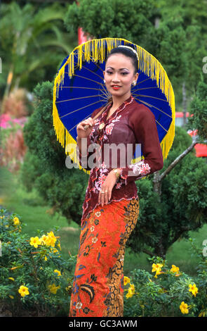 Malaysische Mädchen gekleidet in traditioneller Tracht mit bunten Regenschirm Stockfoto