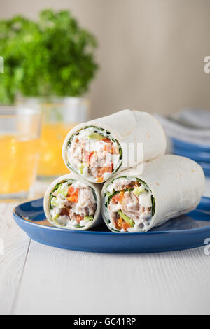 Thunfisch-Wraps mit Avocado-Tomaten-Mayonnaise auf blaue Platte Stockfoto