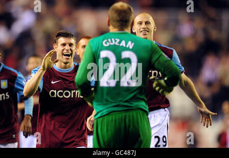 James Milner (links) und Danny Collins (rechts) von Aston Villa gratulieren Torhüter Brad Guzan nach ihrem Sieg im Elfmeterschießen gegen Sunderland während des Carling Cup-Spiels im Stadium of Light, Sunderland. Stockfoto