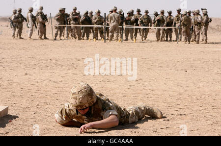 Ein britischer Armeesoldat bei einer Trainingsübung auf der Suche nach improvisierten Sprengvorrichtungen (IEDs) im Camp Bastion in Afghanistan mit amerikanischen Marineinfanteristen in der Ferne. Stockfoto