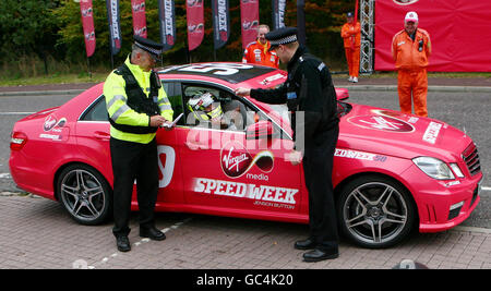 FOTO-AUFBAU Formel-1-Weltmeister Jenson Button, wird von Polizisten der Polizei von Kent beim Fahren eines Sport-Mercedes während eines Auftritts im Bluewater Einkaufszentrum in Greenhithe, Kent, mit einem Speeding-Ticket ausgestattet. Stockfoto