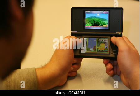 Computerspiel. Ein Mann spielt ein Spiel auf einer Nintendo DS Konsole. Stockfoto