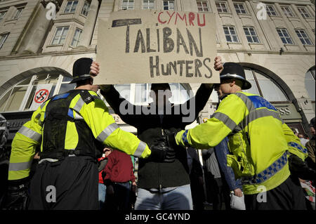 Ein Protestler der Walisischen Verteidigungsliga hält ein selbstgemachtes Plakat mit der Aufschrift „Cymru Taliban Hunters“, da die Their-Gruppe während eines Protestes in der Nähe des Castle Square in Swansea, Wales, von den antifaschistischen Demonstranten von der Polizei getrennt wird. Stockfoto