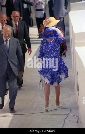 Königin Elizabeth II. Hält sich an ihrem Hut fest, als der Wind nach der Einweihung des Belagerungsglockendenkmals in Valetta, Malta, unerwartet zunahm. Stockfoto