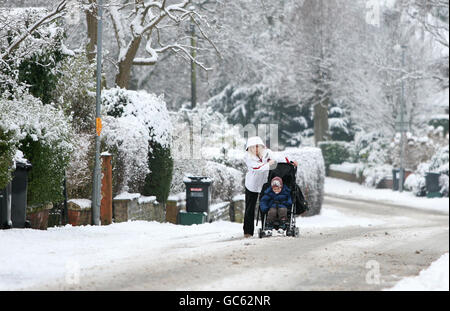 Eine Frau kämpft darum, ihren Buggy in Knutsford, Ceshire, auf einer ungeschanzten Straße zu schieben. Stockfoto