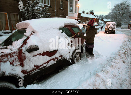 Winterwetter. Eine Frau räumt in St. Boswells an der schottischen Grenze nach einer Nacht mit starkem Schneefall Schnee aus ihrem Auto. Stockfoto