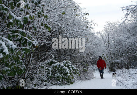 Eine Frau geht mit ihrem Hund in Bingham, Nottinghamshire, als eine frische Schneeflut über Nacht wieder Elend für Reisende brachte. Stockfoto