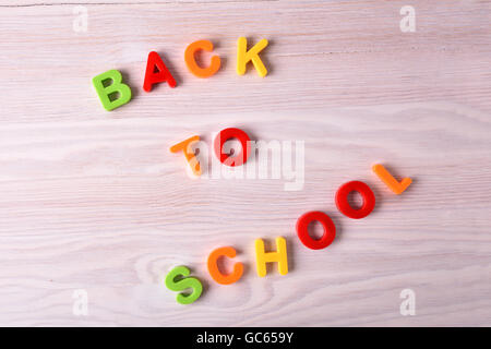 Zurück zum Schulkonzept mit bunten Buchstaben auf einem braunen Holz Schreibtisch. Ansicht von oben Stockfoto