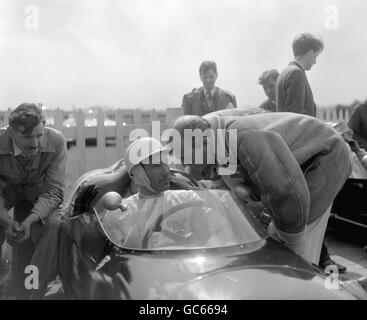 Stirling Moss, britischer Rennfahrer, saß in einem Porsche des RRC Walker Racing Teams und sprach mit Rennfahrer Harry Schell, bevor er die Goodwood-Rennstrecke zur Vorbereitung auf das britische Automobilevent am Ostermontag einläd. Stockfoto