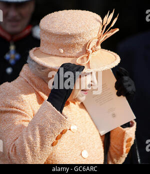 Die britische Königin Elizabeth II. Hält sich bei einem Besuch in der Ely Cathedral an ihren Hut. Stockfoto