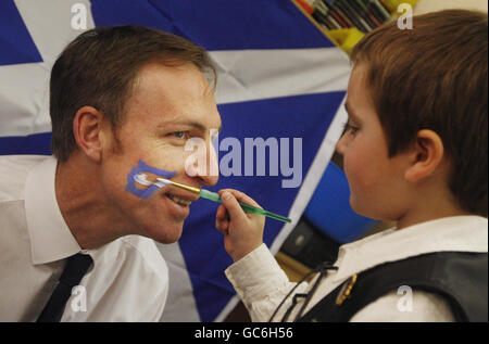 Jim Murphy, Staatssekretär für Schottland, lässt sein Gesicht mit einem Saltyre bemalen, während eines Besuchs im Madras Family Center Kinderzimmer in Neilston, um den St. Andrew's Day zu feiern. Stockfoto