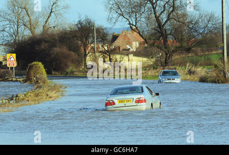 Flutgewässer betreffen noch heute viele Teile Großbritanniens, da die steigenden Flussniveaus in North Yorkshire nahe Northallerton verlassene Fahrzeuge auf der Straße verlassen. Stockfoto