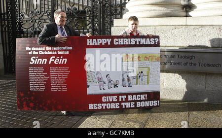 Sinn Fein TD Aengus O'Slodaigh und Curtis Tysom liefern heute eine riesige Weihnachtskarte, die von dem 12-Jährigen entworfen wurde, an Regierungsgebäude in Dublin, um den Finanzminister Brian Lenihan dazu zu bringen, die Weihnachtsgeld-Zahlung im morgigen Haushalt wiederherzustellen. Stockfoto