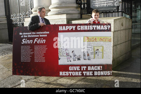 Sinn Fein TD Aengus O'Slodaigh und Curtis Tysom liefern heute eine riesige Weihnachtskarte, die von dem 12-Jährigen entworfen wurde, an Regierungsgebäude in Dublin, um den Finanzminister Brian Lenihan dazu zu bringen, die Weihnachtsgeld-Zahlung im morgigen Haushalt wiederherzustellen. Stockfoto