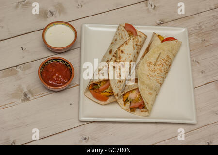 Burritos, gefüllt mit Hühnerfleisch, Paprika, Reis und Tomaten mit Salsa und sour Creme auf der Seite Stockfoto